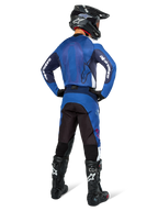 Alpinestars Pro-Dura broek, motorcross- en endurobroek, marineblauw, helderblauw en wit, achteraanzicht, gedragen met bijpassende blauwe jersey, zwarte helm en zwarte Tech-laarzen, duurzame constructie met stretch-inzetstukken voor off-road rijden