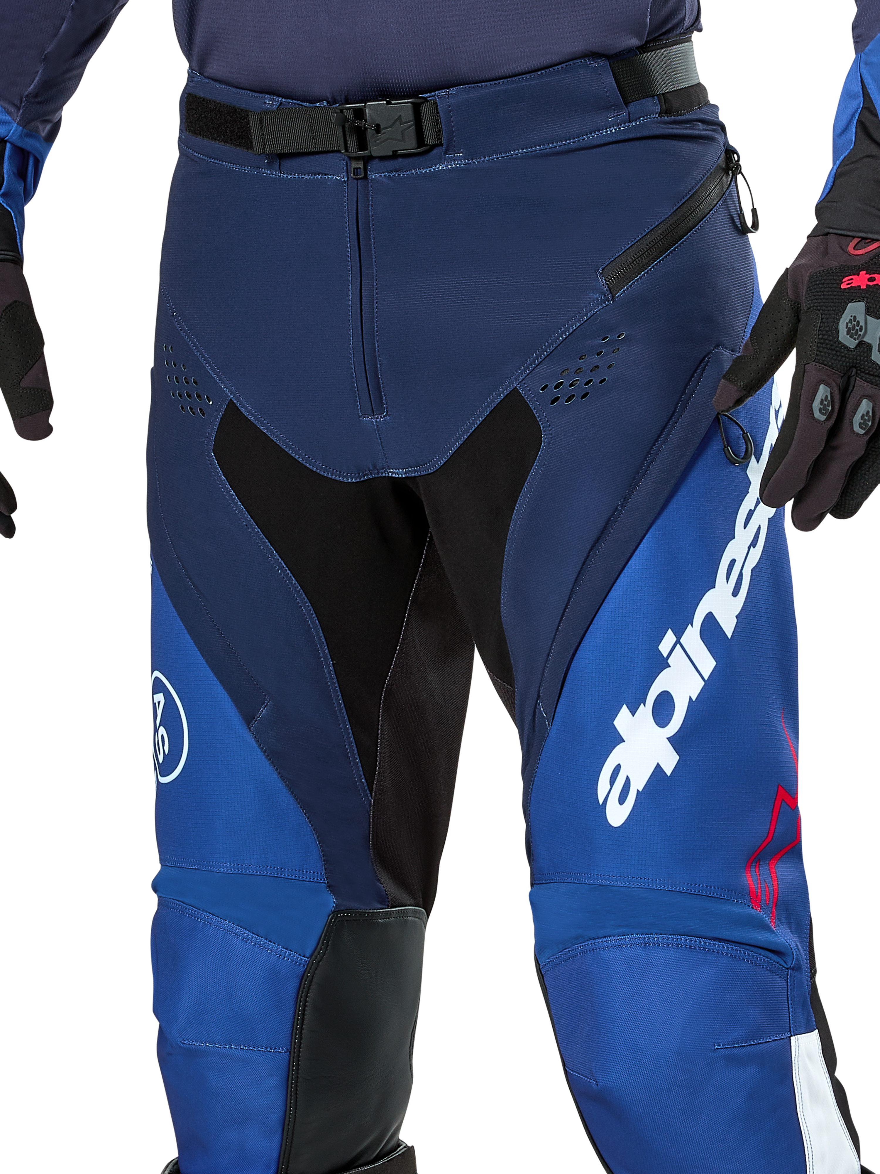 Alpinestars Pro-Dura broek, enduro- en motorcrossbroek, marineblauw, felblauw en wit, detailopname van de SX2 magnetische gespsluiting in de taille, ventilatieopeningen met rits op de dijen en duurzame stretchpanelen met opvallende witte merkdetails.