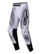 Alpinestars 2025 Supertech Maker broek, motorcross broek, zilver en zwart, met grote zwarte Astars-logo's op de dijen, rode technische branding op de heup, zwarte lederen binnenkniepanelen en geperforeerde ventilatiezones.