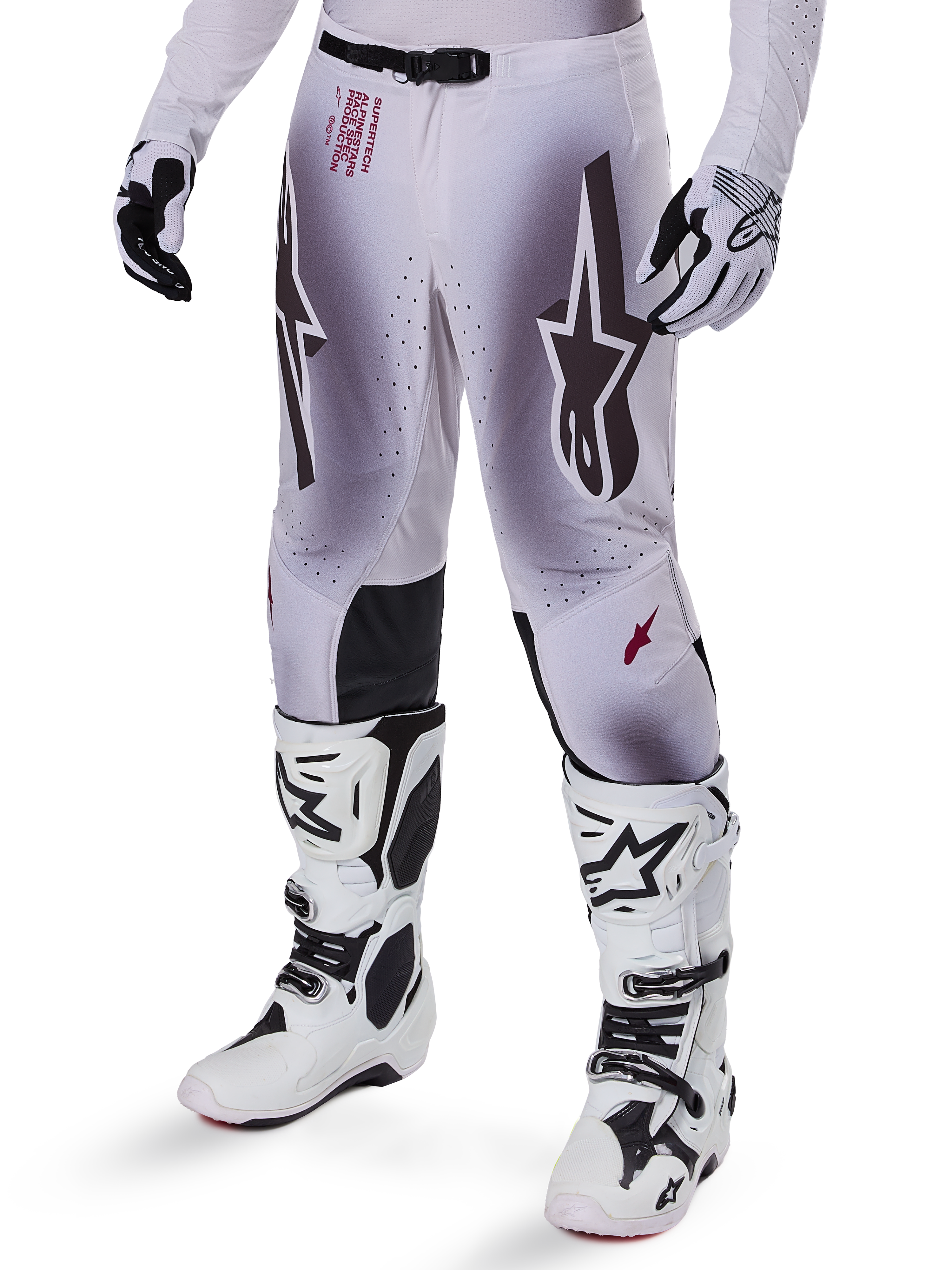 Alpinestars 2025 Supertech Maker crossbroek, motorcross broek, zilver en zwart, met grote sterlogo's en rode belettering, getoond met bijpassende witte laarzen en handschoenen