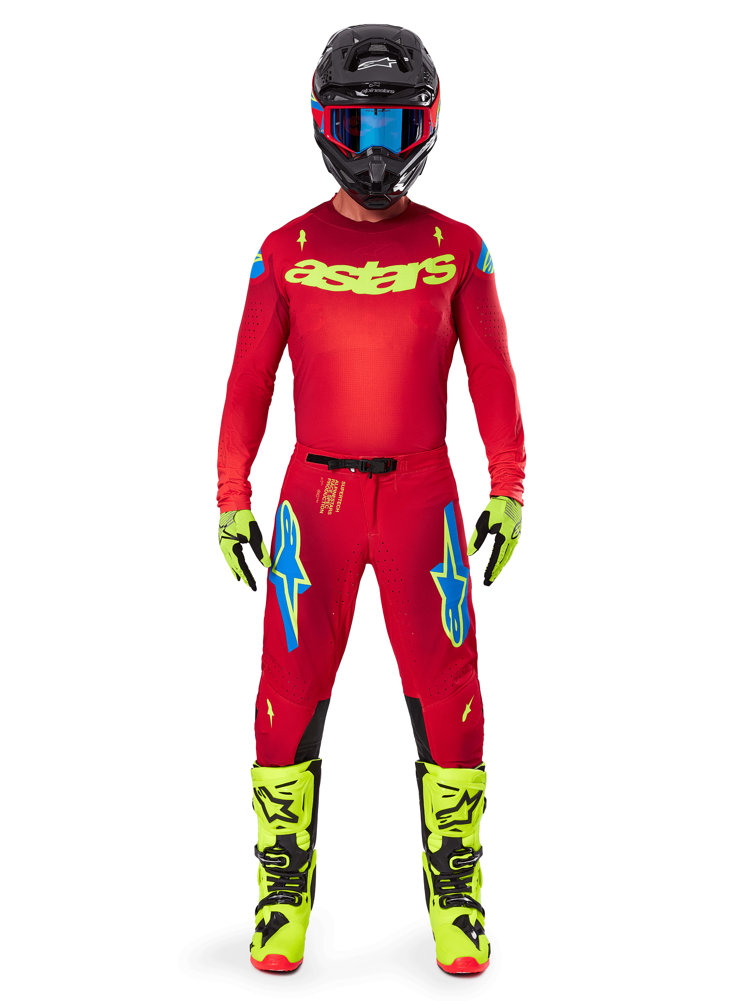 Motocross rider wearing complete racing gear, Red jersey with yellow fluo astars logo, Alpinestars 2025 Supertech Maker Pants in Bright Red and Yellow Fluo, featuring blue logos on thighs, yellow fluo gloves and boots, black helmet with blue goggles, coordinated pro-level motocross outfit
