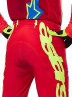Alpinestars 2025 Supertech Maker Pants, Motocross Pants, Bright Red and Yellow Fluo, rear close-up showing bold neon yellow graphics, worn with matching red jersey and yellow/black gloves