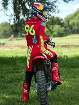 Alpinestars 2025 Supertech Maker broek in Bright Red en Yellow Fluo, motorcross-rijder op een rode crossmotor, bijpassende rode jersey met '96' en 'LAWRENCE' op de rug, rode motorcrosslaarzen en Red Bull-helm, professionele off-road race-uitrusting