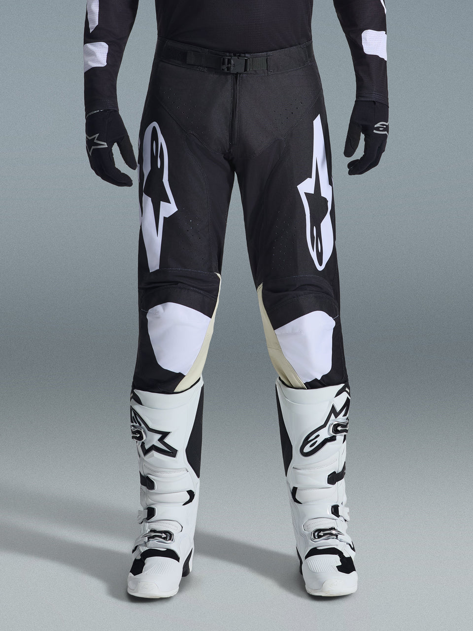 Alpinestars 2026 Racer Air Riway Pants, Motocross Pants, Black and White, featuring bold white Alpinestars logos on the thighs and knee panels, paired with white and black motocross boots and black gloves, athletic race-fit design for off-road riding