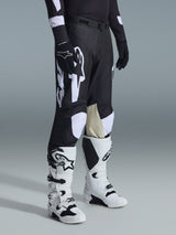 Alpinestars 2026 Racer Air Riway Pants, Motocross Pants, Black and White, worn with white and black Tech Series boots and black long-sleeve jersey, featuring white Alpinestars branding, laser-cut perforations, and tan goat leather inner knee panels for off-road performance.