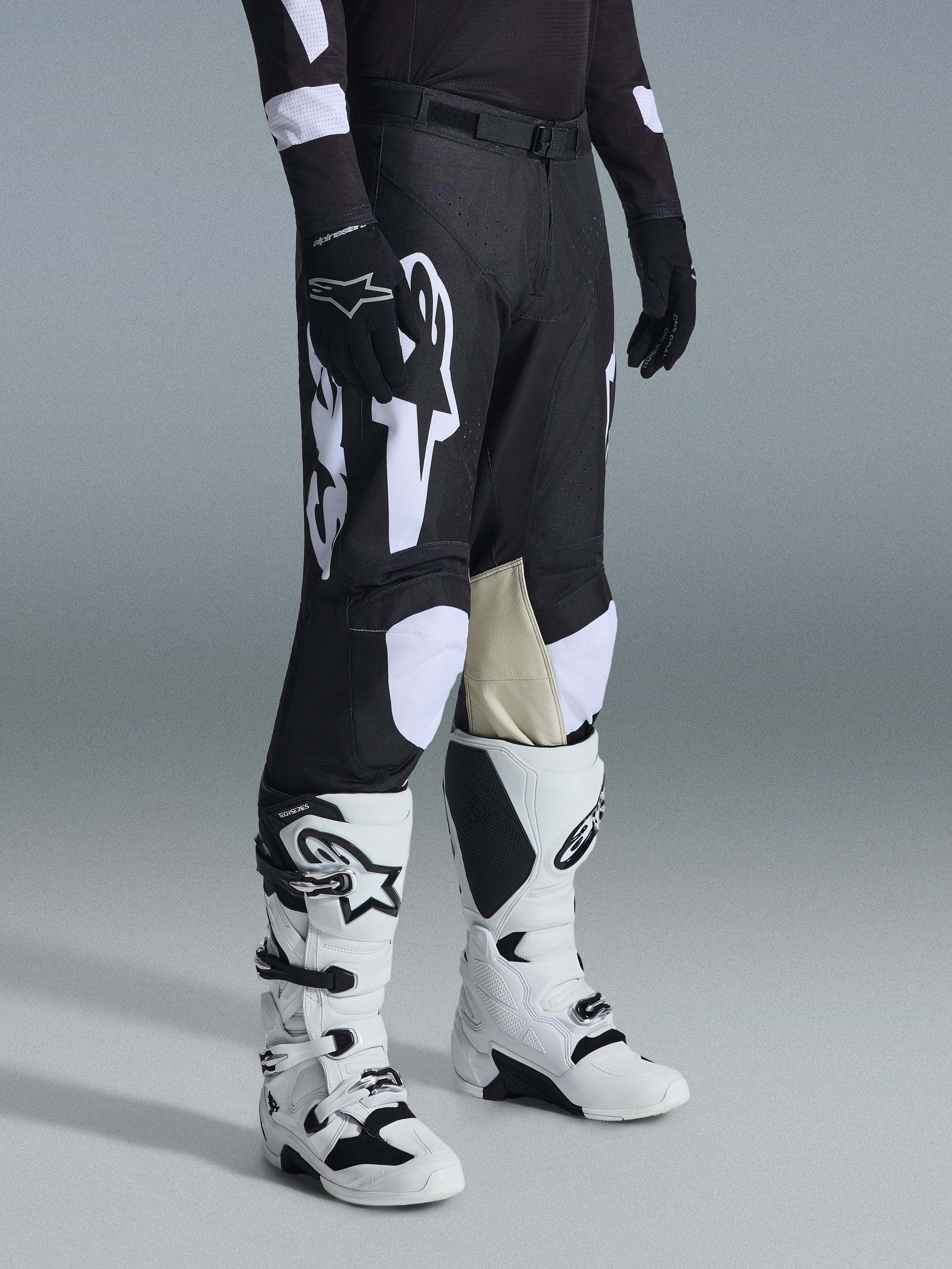 Alpinestars 2026 Racer Air Riway Pants, Motocross Pants, Black and White, worn with white and black Tech Series boots and black long-sleeve jersey, featuring white Alpinestars branding, laser-cut perforations, and tan goat leather inner knee panels for off-road performance.