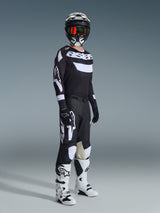 Motocross rider wearing 2026 Racer Air Riway Pants, Black and White, matching jersey with Alpinestars logo, black helmet with goggles, white and black boots, full gear set for off-road motocross performance