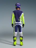 Motocross rider from the back wearing the Alpinestars 2026 Racer Air Riway Pants in Light Gray, Yellow Fluo, and Blue, paired with a matching jersey and bright yellow boots, illustrating a complete professional off-road racing gear set.