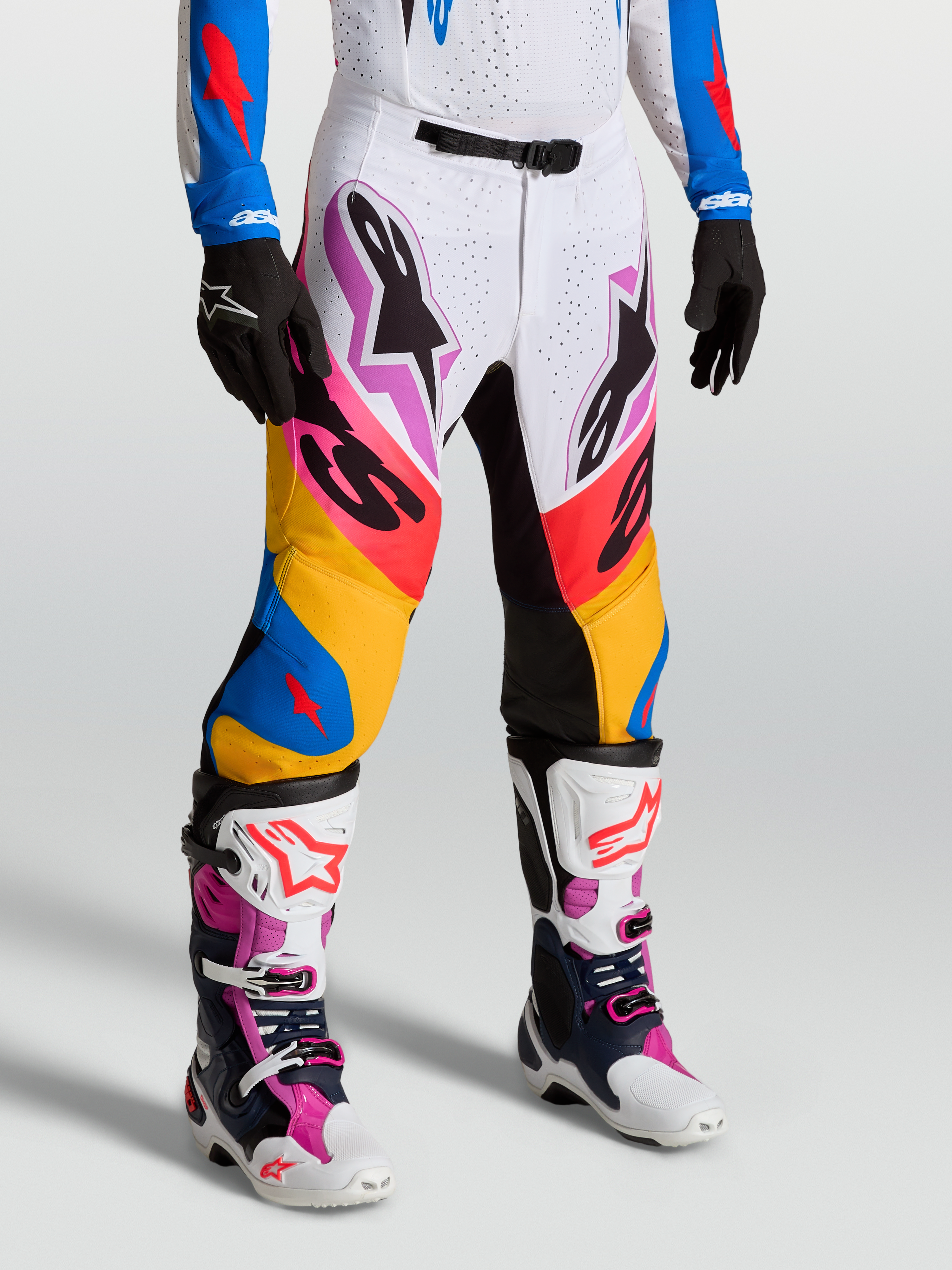 Alpinestars Supertech Dyna Pants in white and blithe blue, premium motocross racing pants on-model with stretch rip-stop fabric and goat leather knee panels.