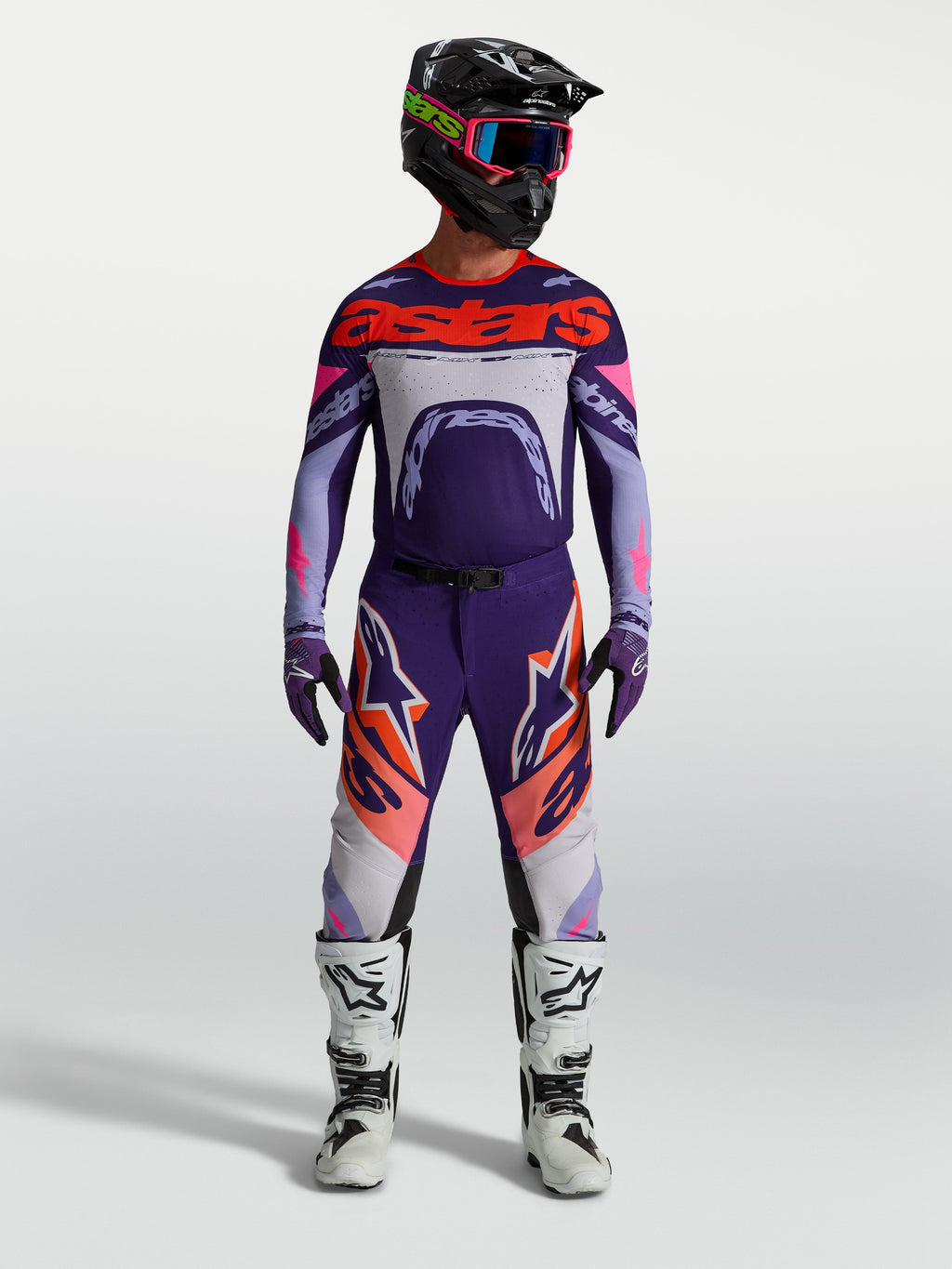 Alpinestars Supertech Dyna broek en gear set, heren motocross-outfit, paars en roze fluo met jersey en witte motorlaarzen.