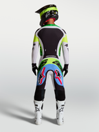Alpinestars Supertech Dyna broek, motocrossbroek, lichtlila en fluorgroen, achteraanzicht van rijder in race-uitrusting.