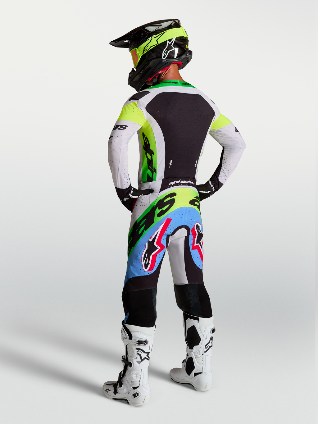 Alpinestars Supertech Dyna motocrossuitrusting in groen fluo, zwart en licht lila, met racebroek en jersey, achteraanzicht.