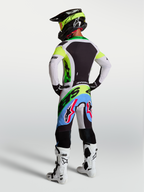 Alpinestars Supertech Dyna motocrossuitrusting in groen fluo, zwart en licht lila, met racebroek en jersey, achteraanzicht.