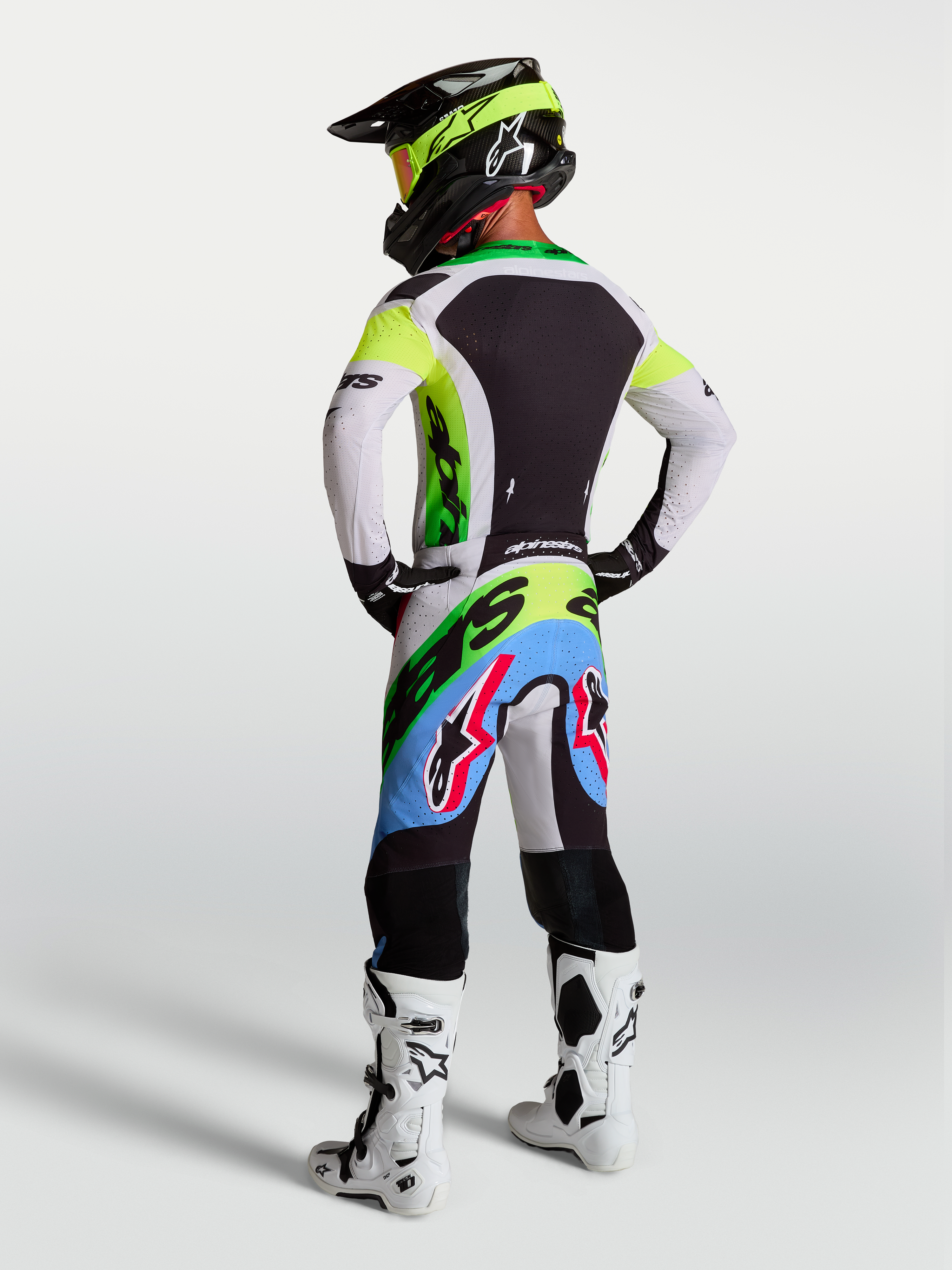 Alpinestars Supertech Dyna motocrossuitrusting in groen fluo, zwart en licht lila, met racebroek en jersey, achteraanzicht.