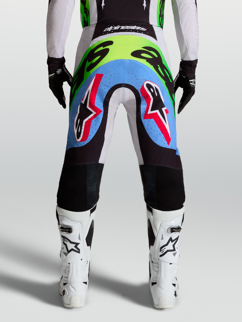 Alpinestars Supertech Dyna heren-motocrossbroek, achteraanzicht in licht lila en fluorgroen met geperforeerde stretchpanelen.