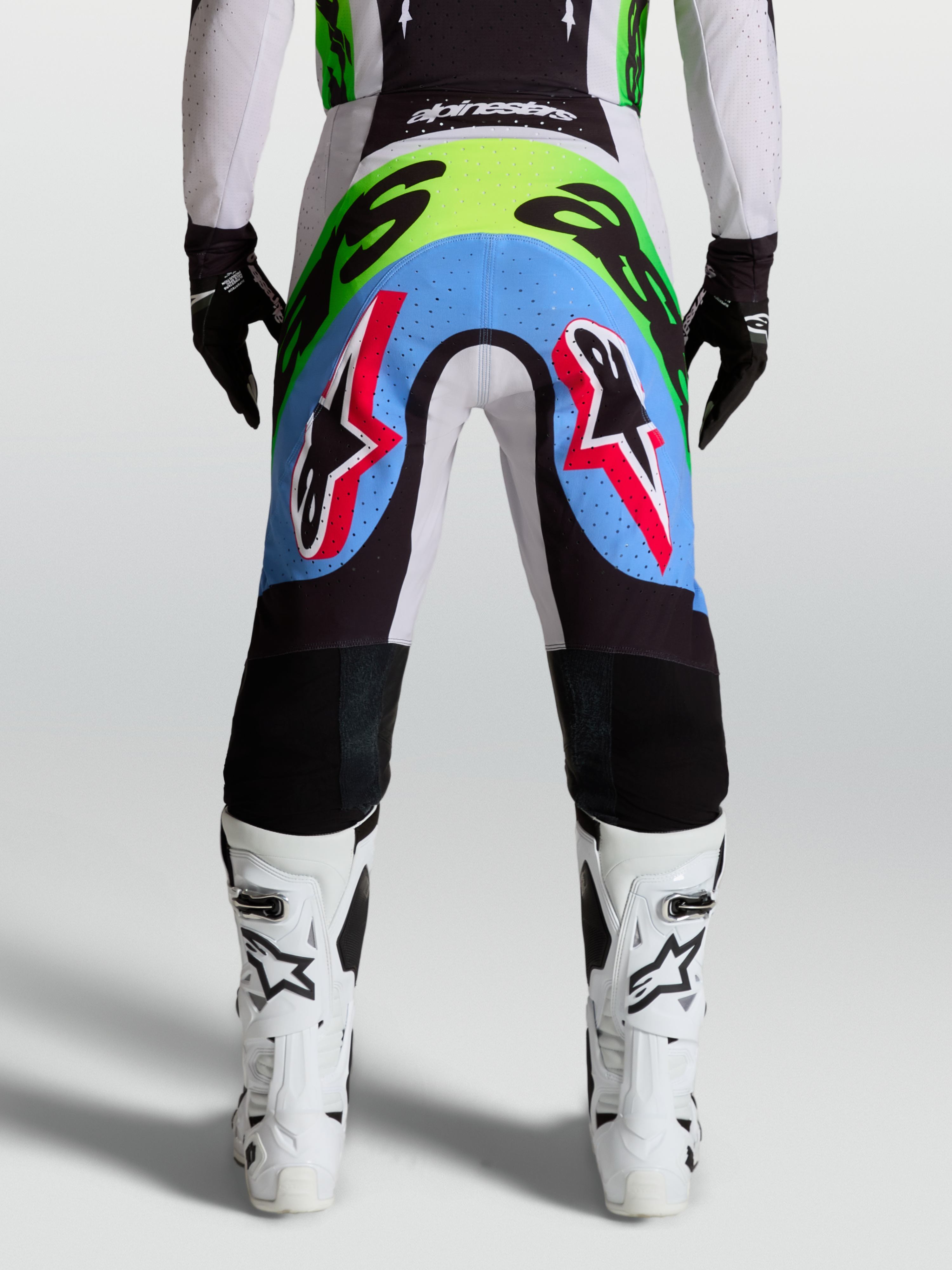 Alpinestars Supertech Dyna heren-motocrossbroek, achteraanzicht in licht lila en fluorgroen met geperforeerde stretchpanelen.