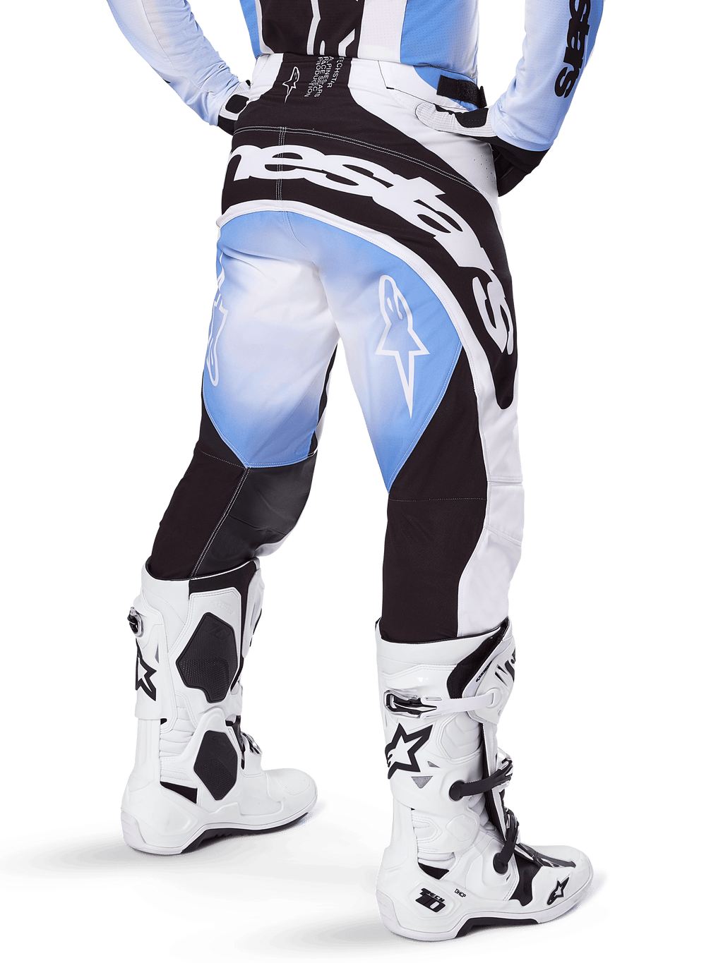 Alpinestars 2025 Techstar Melt crossbroek, motorcrossbroek, zwart, blauw en wit, achteraanzicht met opvallend Alpinestars-woordmerk op het zitvlak en sterlogo's op de pijpen, gedragen met witte en zwarte Tech 10-laarzen, professionele off-road race-uitrusting