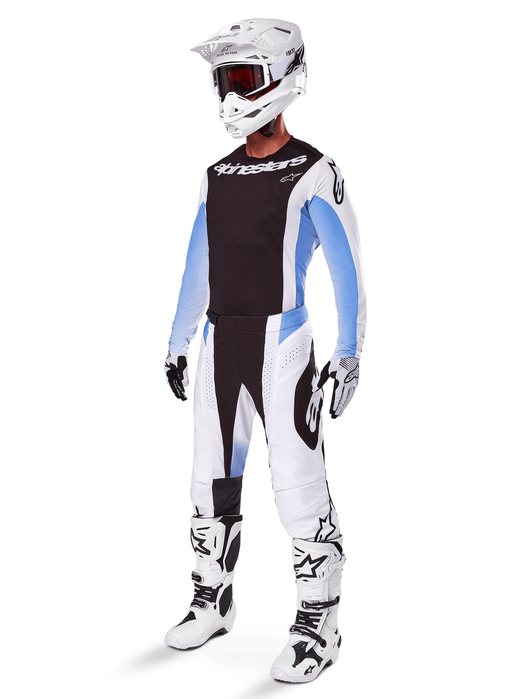 Motorcrossrijder in de Alpinestars 2025 Techstar Melt broek, wit-zwarte motorcrosskleding met lichtblauwe accenten, bijpassende jersey en handschoenen, witte helm en crossbril, witte en zwarte racelaarzen, professionele off-road uitrusting.