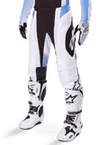 Alpinestars 2025 Techstar Melt crossbroek, motorcross broek, wit en zwart met blauwe accenten, met laser-gesneden perforaties voor luchtstroom en Babel-knieconstructie, gedragen met bijpassende witte motorcrosslaarzen en handschoenen, atletisch off-road race-ontwerp