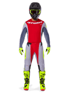 Motorcrossrijder in de Alpinestars 2025 Techstar Melt Gear Set in Bright Red Gray, met een rode jersey met grijze mouwen, een grijze broek met rode en fluorescerend gele accenten, bijpassende neongele laarzen en handschoenen, en een zwarte helm met een neongele crossbril.