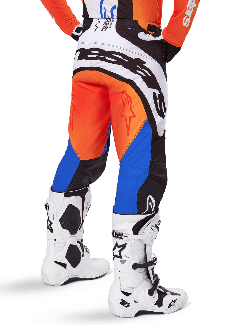 Alpinestars 2025 Techstar Melt broek, motorcross broek, oranje en blauw, van achteren gezien, met groot wit logo op het zitvlak, gedragen met bijpassend oranje shirt en witte Tech 10 laarzen, duurzame off-road race-uitrusting