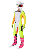 Alpinestars 2025 Techstar Melt Gear Set, volledige motorcross race-outfit, wit jersey met geel-oranje mouwen, neongele broek, felroze laarzen, witte helm met rode crossbril, gele handschoenen, kleurrijke racekleding