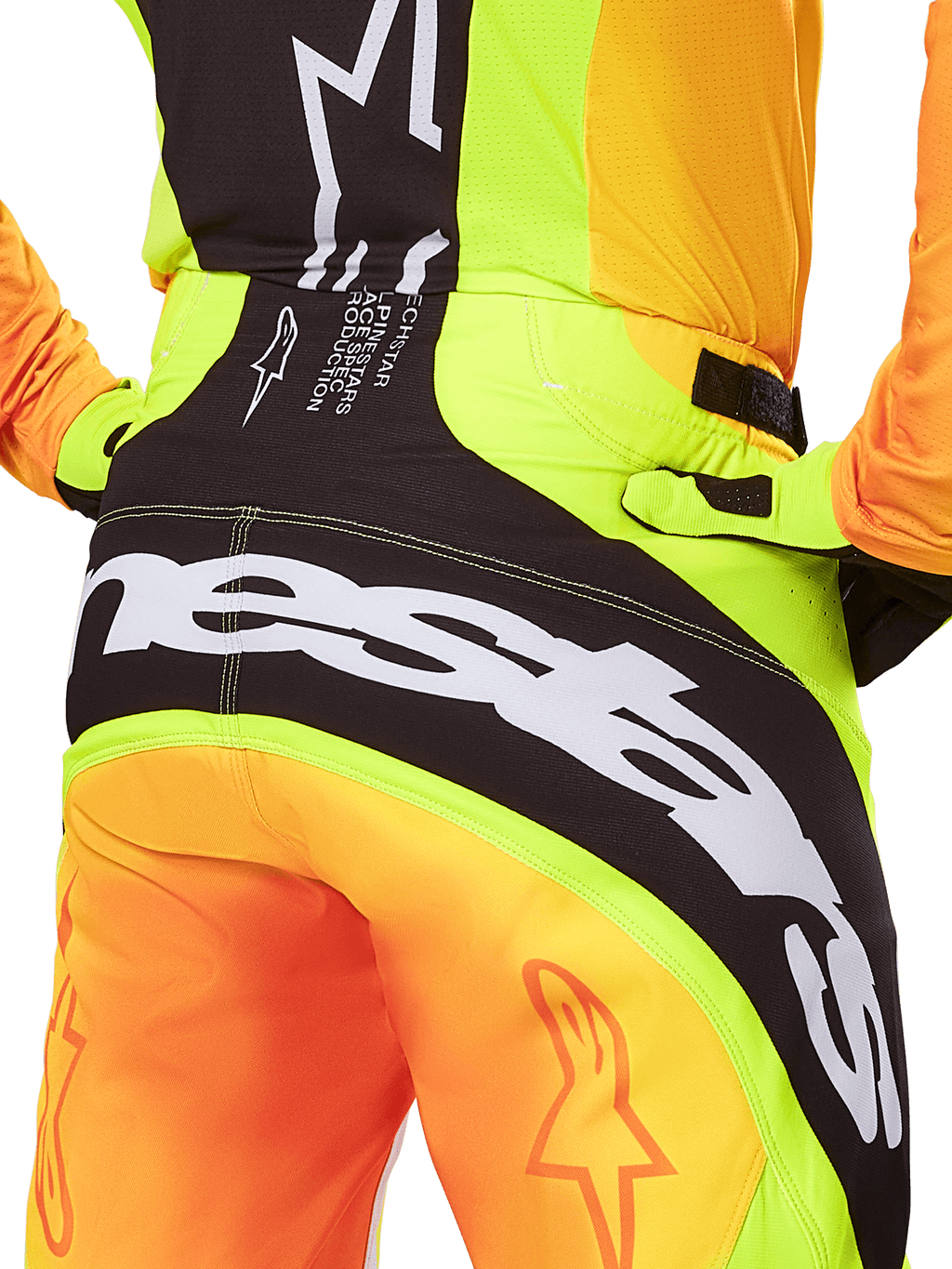 Alpinestars 2025 Techstar Melt crossbroek, motorcross broek, close-up van de achterkant, neongeel en oranje met zwarte panelen, groot wit Alpinestars-logo over het zitvlak, technische off-road motorkleding