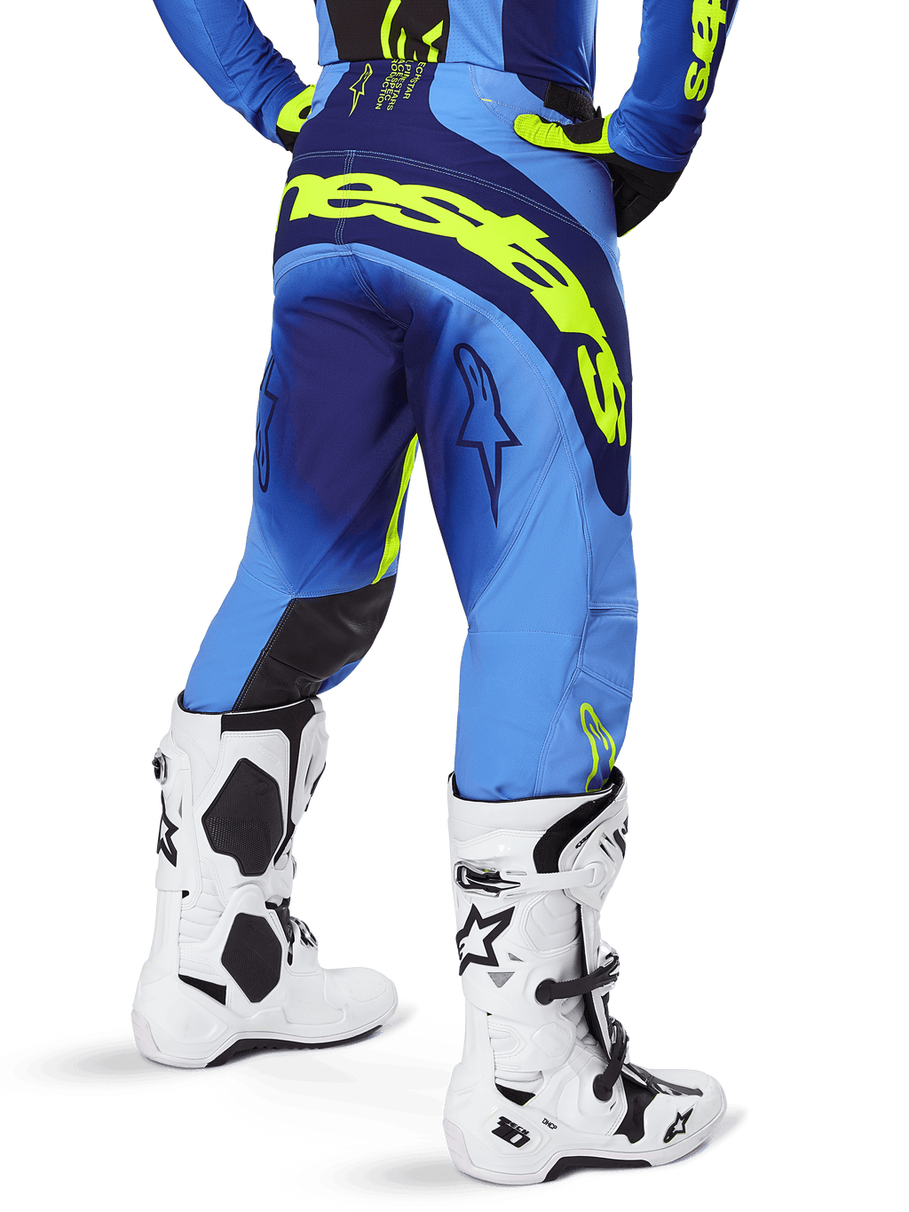 Alpinestars 2025 Techstar Melt crossbroek, motorcross broek, blauw en fluogeel, achteraanzicht met grote gele branding op het zitvlak en de dijen, gedragen met witte motorcrosslaarzen en bijpassende blauwe jersey, atletische racepasvorm voor off-road rijden