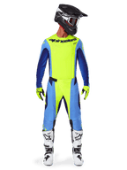 Alpinestars 2025 Techstar Melt broek, motorcrossbroek, fluogeel blauw, gedragen met bijpassende jersey, gele handschoenen en witte en zwarte laarzen, voorzien van een zwarte helm met rode bril, complete race-uitrusting voor off-road prestaties