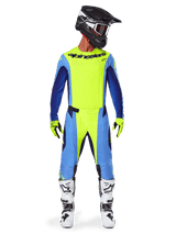Alpinestars 2025 Techstar Melt broek, motorcrossbroek, fluogeel blauw, gedragen met bijpassende jersey, gele handschoenen en witte en zwarte laarzen, voorzien van een zwarte helm met rode bril, complete race-uitrusting voor off-road prestaties