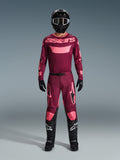 Motocrossrijder in de Alpinestars 2026 Racer Riway Gear Set, maroon jersey met roze 'astars' branding, bijpassende maroon broek met roze knie- en beenaccenten, zwarte helm, zwarte handschoenen en zwarte laarzen, complete performance outfit voor off-road racing