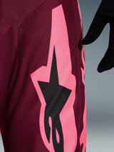 Alpinestars 2026 Racer Riway broek, motorcross broek, Dark Red Coral, detailopname van een grote hoekige koraalroze graphic en zwart sterlogo, met focus op de duurzame polyfabric textuur en prestatiegerichte stiksels.