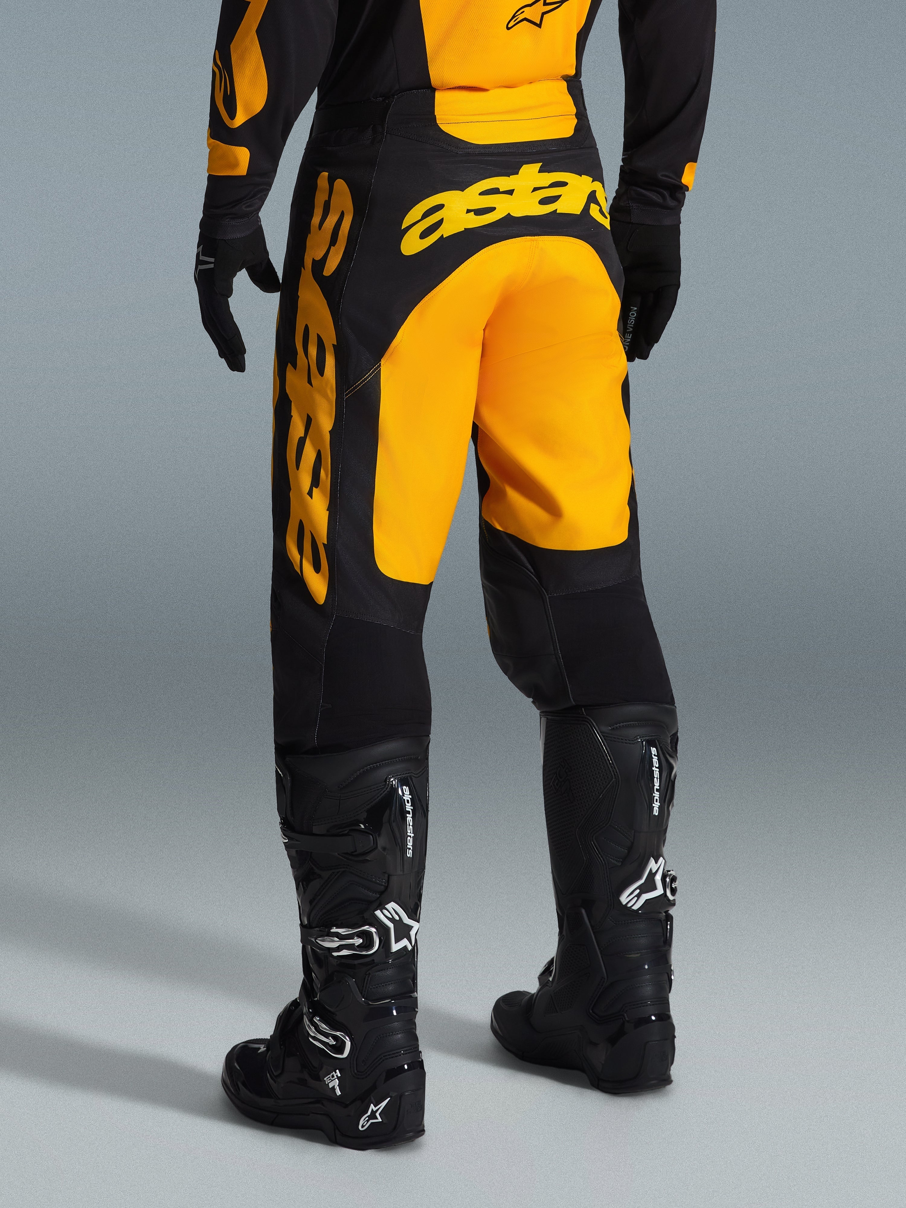 Alpinestars 2026 Racer Riway broek, motorcross broek, geel met zwart, achteraanzicht met opvallende gele astars-branding op het zitvlak en de broekspijp, gecombineerd met zwarte motorcrosslaarzen en handschoenen