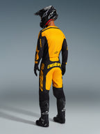 Achteraanzicht van een motorcrosser die de Alpinestars 2026 Racer Riway broek draagt in geel en zwart, met bijpassende jersey, zwarte helm en zwarte laarzen, gecoördineerde race-uitrusting voor off-road prestaties.