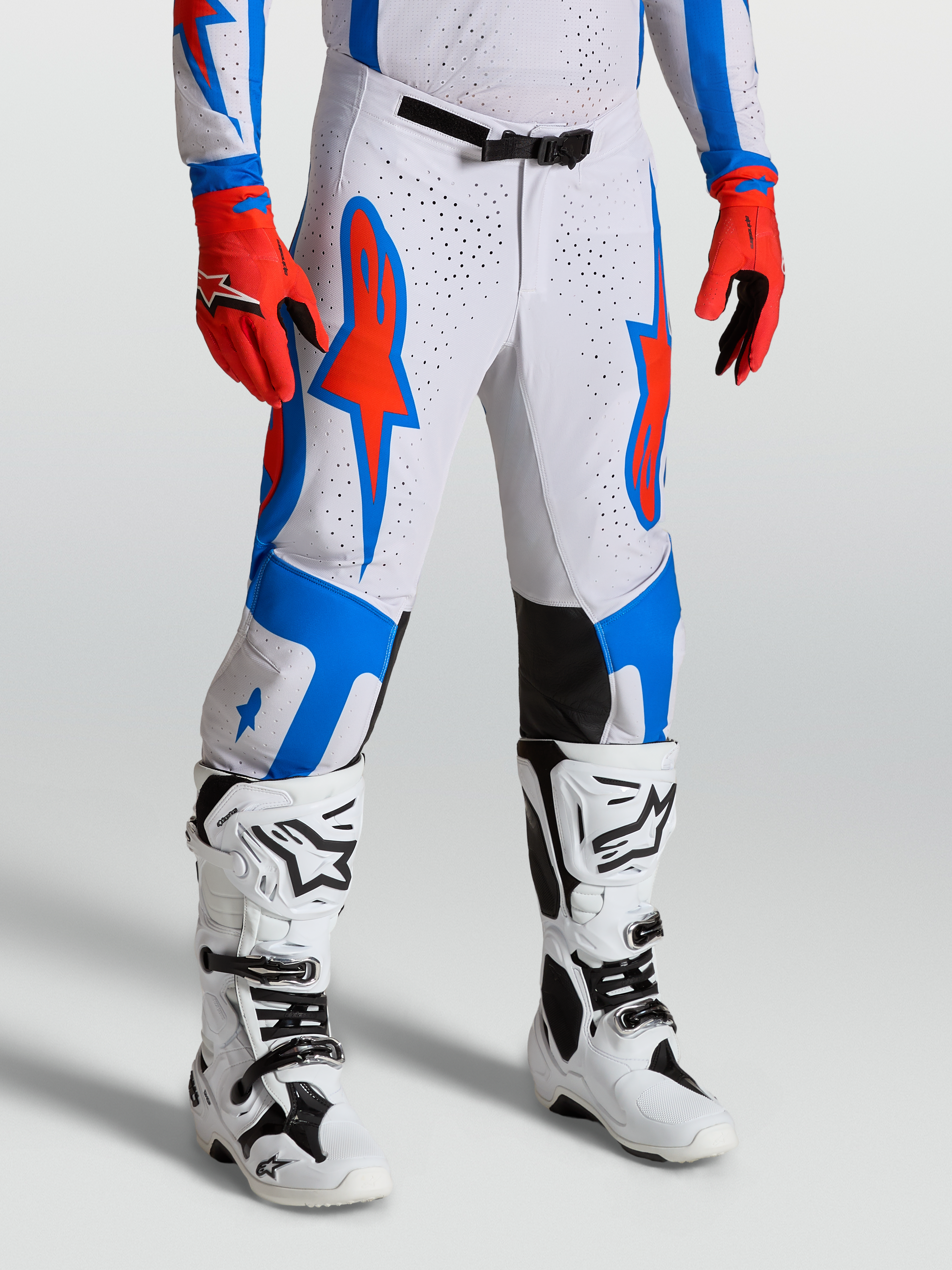 Alpinestars Supertech Vesta broek, motocrossbroek in wit en rood met blauwe ster-graphics, atletische racepasvorm.