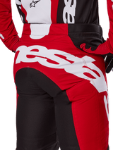 Alpinestars 2025 Racer Veil crossbroek, motorcross broek, zwart en felrood, close-up van het zitvlak met een groot wit Alpinestars-woordmerklogo, rode en zwarte technische panelen, gedragen met bijpassende uitrusting