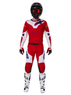 Alpinestars 2025 Racer Veil broek en complete motorcross uitrusting, felrood en wit met blauwe accenten, met bijpassende jersey, zwarte helm met oranje crossbril, witte en zwarte laarzen en rode handschoenen, gecoördineerde performance-look voor off-road racen.