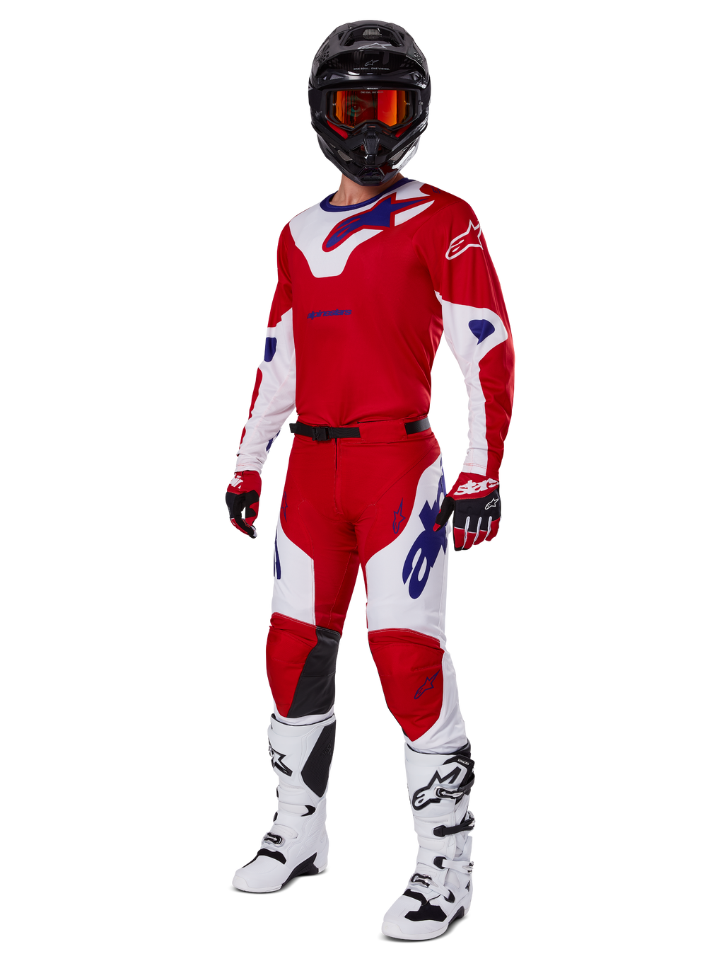Alpinestars 2025 Racer Veil broek, motorcrossbroek, helder rood en wit, gedragen als onderdeel van een complete race-uitrusting inclusief een bijpassend rood en wit shirt, zwarte helm met oranje bril, witte laarzen en rode handschoenen, met opvallende blauwe Alpinestars-logo's.