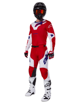 Alpinestars 2025 Racer Veil Pants, Motocross Pants, Bright Red and White, worn as part of a complete racing gear set including a matching red and white jersey, black helmet with orange goggles, white boots, and red gloves, featuring bold blue Alpinestars logos.