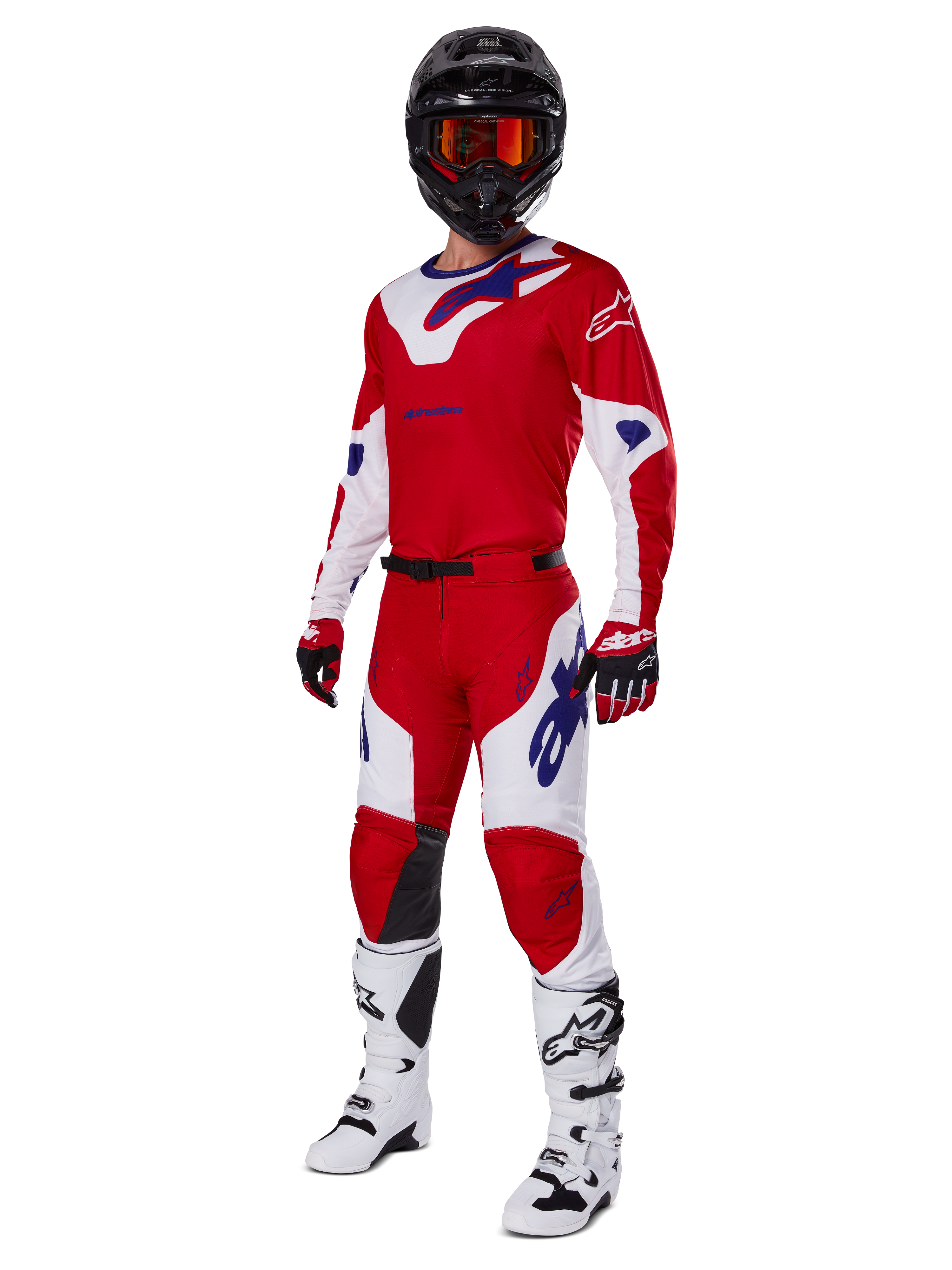 Alpinestars 2025 Racer Veil broek, motorcrossbroek, helder rood en wit, gedragen als onderdeel van een complete race-uitrusting inclusief een bijpassend rood en wit shirt, zwarte helm met oranje bril, witte laarzen en rode handschoenen, met opvallende blauwe Alpinestars-logo's.