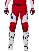 Alpinestars 2025 Racer Veil Pants, Motocross Pants, Bright Red and White, worn with matching red gloves and white boots, featuring blue branding on the thighs and a black waist belt, ergonomic sport cut for performance riding