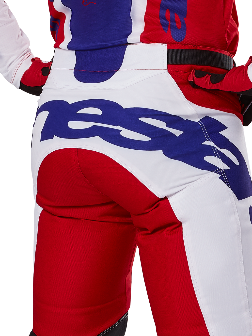 Alpinestars 2025 Racer Veil Pants, motorcrossbroek, felrood en wit met blauwe branding, detail van de achterkant van het zitvlak met een groot Alpinestars-logo, gedragen als onderdeel van een gecoördineerde off-road race-outfit