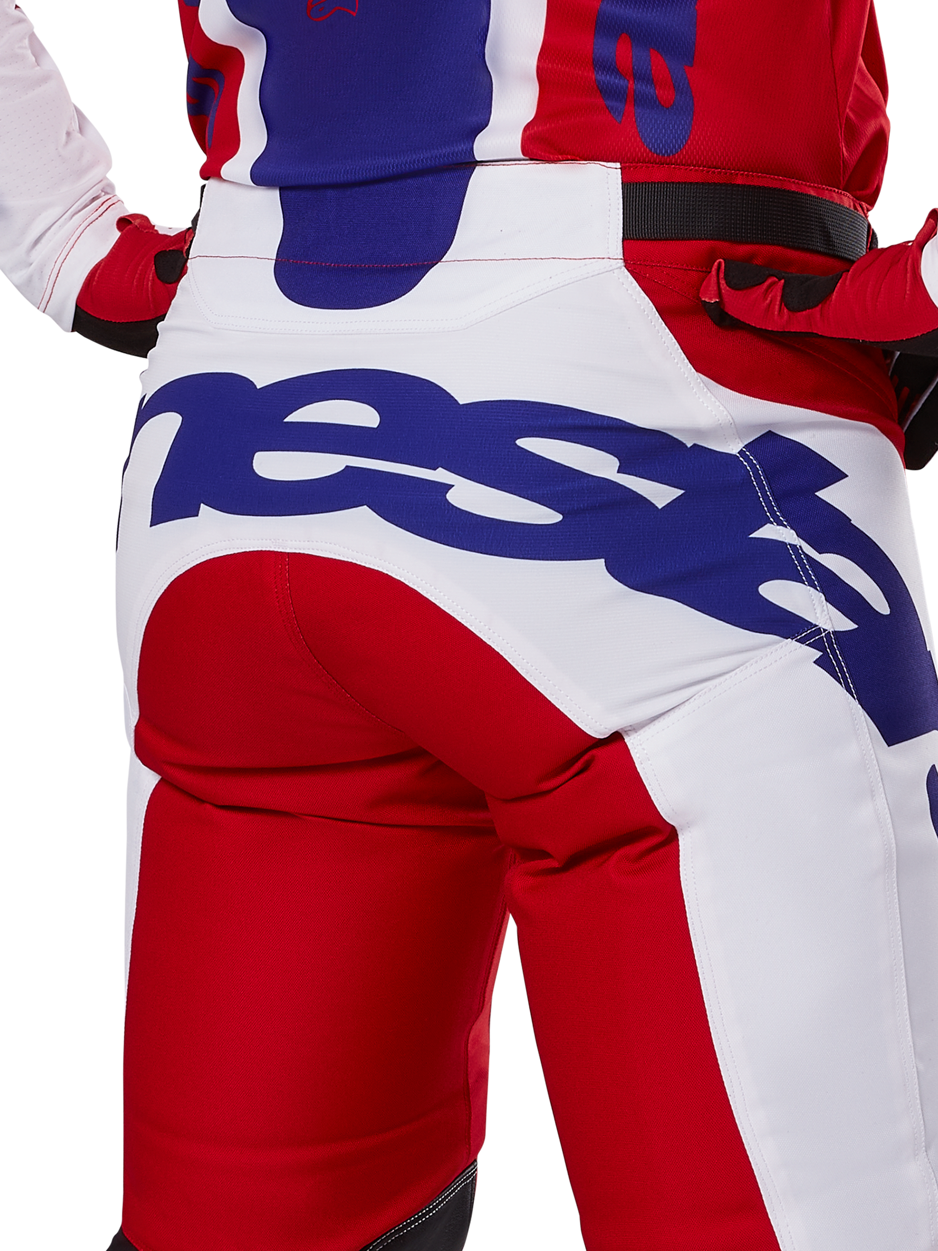 Alpinestars 2025 Racer Veil Pants, motorcrossbroek, felrood en wit met blauwe branding, detail van de achterkant van het zitvlak met een groot Alpinestars-logo, gedragen als onderdeel van een gecoördineerde off-road race-outfit