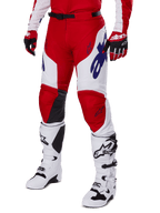 Alpinestars 2025 Racer Veil Pants, motorcrossbroek, helderrood en wit, met blauwe Alpinestars-logo's en zwarte lederen binnenkniepanelen, gedragen met bijpassende rode handschoenen en witte motorcrosslaarzen, gecoördineerde uitrustingsset voor off-road racing