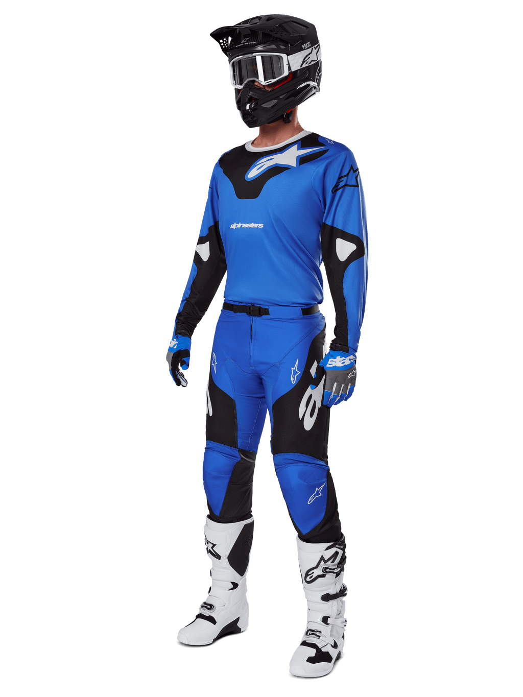 Motocrossrijder in volledige race-uitrusting, met Alpinestars 2025 Racer Veil broek in blauw en zwart, bijpassende blauwe jersey met witte accenten, zwarte helm met witte crossbril, witte en zwarte laarzen en blauwe handschoenen, gecoördineerde outfit voor off-road racing