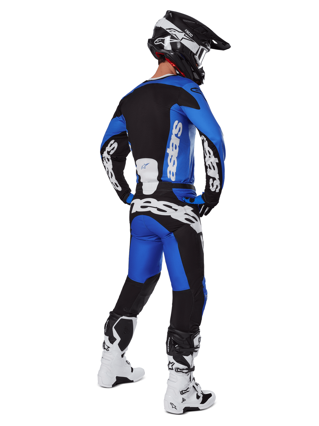 Motorcrossrijder van achteren gezien in Alpinestars 2025 Racer Veil broek in blauw en zwart, bijpassende jersey met lange mouwen en witte branding, witte en zwarte Tech 7 laarzen en een zwarte SM10 helm, volledige off-road race-uitrusting