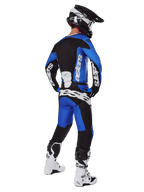 Motorcrossrijder van achteren gezien in Alpinestars 2025 Racer Veil broek in blauw en zwart, bijpassende jersey met lange mouwen en witte branding, witte en zwarte Tech 7 laarzen en een zwarte SM10 helm, volledige off-road race-uitrusting