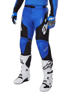 Alpinestars 2025 Racer Veil broek, motorcrossbroek, blauw en zwart met witte grafische accenten, gedragen met bijpassende blauwe jersey, handschoenen en witte laarzen, duurzame beschermende uitrusting voor off-road racen