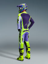 Motorcrossrijder van achteren gezien in de Alpinestars 2026 Racer Portl Pants in Purple Yellow Fluo, gecombineerd met een bijpassend paars en geel shirt, helm en felgele racelaarzen, met opvallende 'astars'-branding op het zitvlak en sterlogo's op de benen.