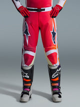 Alpinestars 2026 Racer Portl broek, motorcrossbroek, rood lichtgrijs en donkergrijs, gedragen met bijpassende rode handschoenen en veelkleurige laarzen, met opvallende Alpinestars-sterlogo's op de dijen en witte accenten, sportief ontwerp voor off-road racen